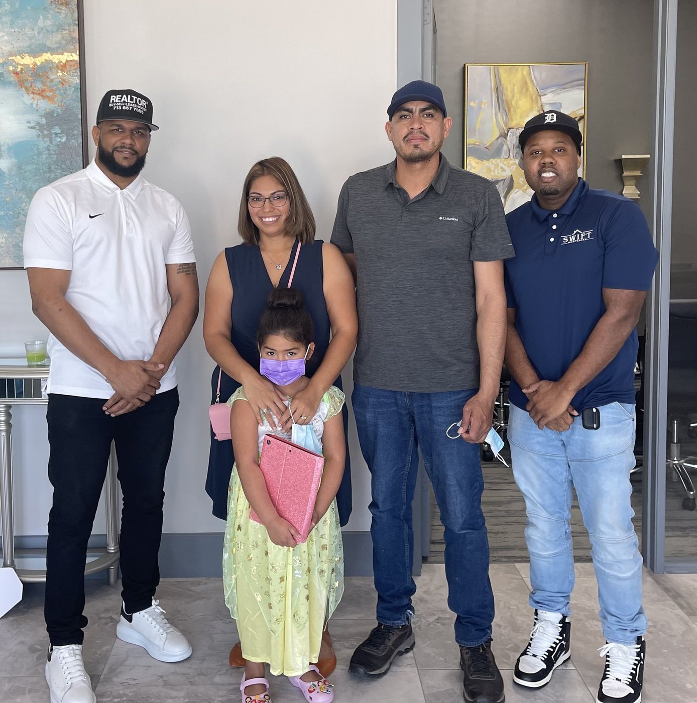 Mr. Wright in a REALTOR cap with a smiling family celebrating at a closing