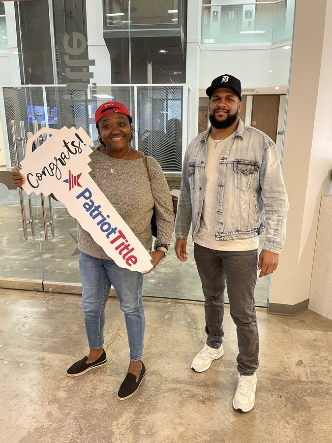 Mr. Wright with a client holding a Congrats key sign in an office lobby