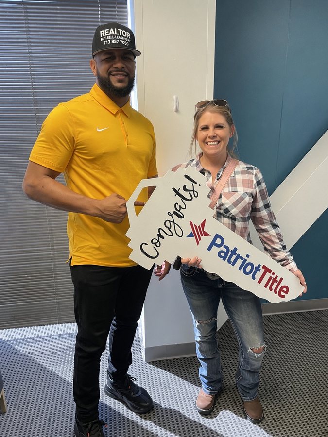 Mr. Wright in a REALTOR cap with a woman holding a Congrats key sign at closing